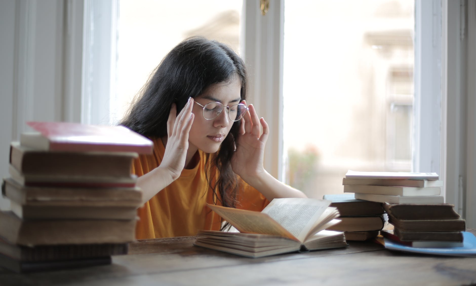 female student suffering from headache in library, dropping out of university