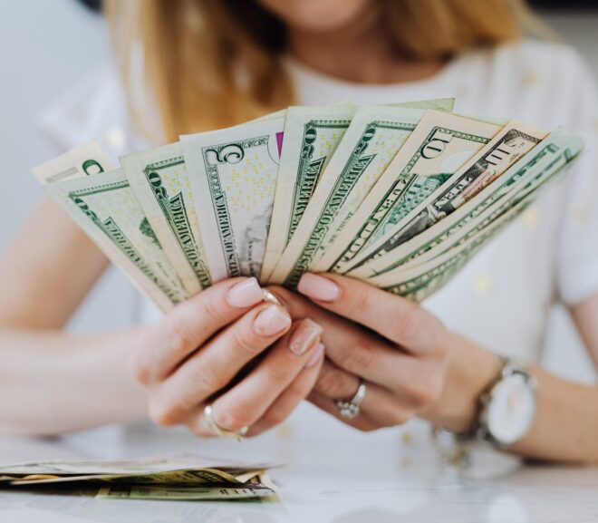 woman holding fan of dollar bills