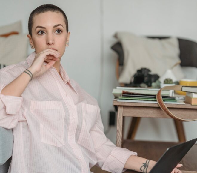 thoughtful young self employed woman looking away during work on netbook at home