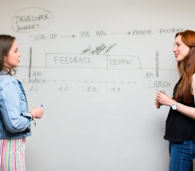 photo of women talking beside whiteboard