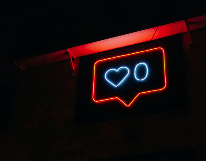 Instagram heart in neon red on black ground next to a zero