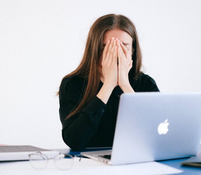 woman with hands on her face in front of a laptop