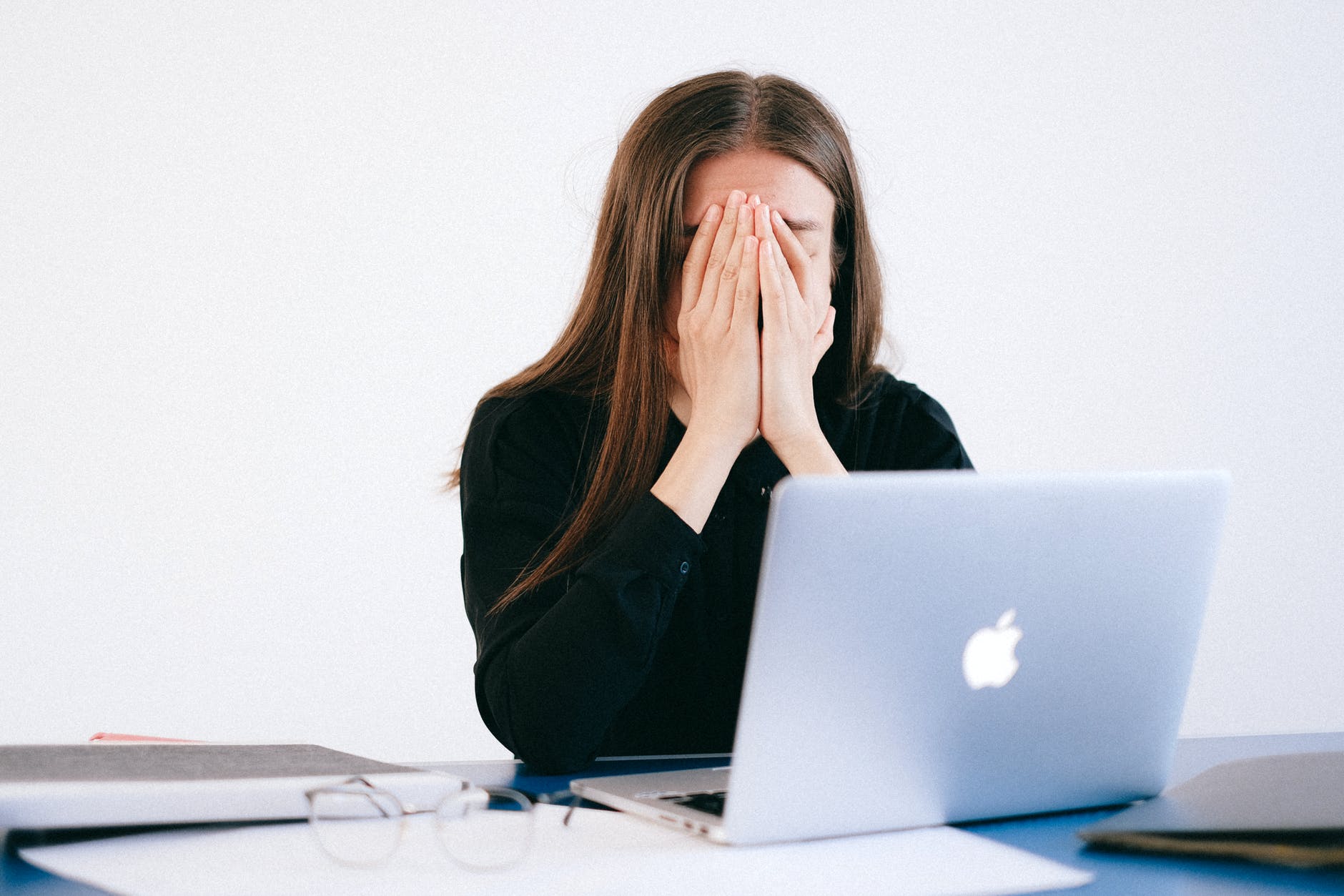 woman with hands on her face in front of a laptop, how to ask for help at work when your workload is overwhelming.