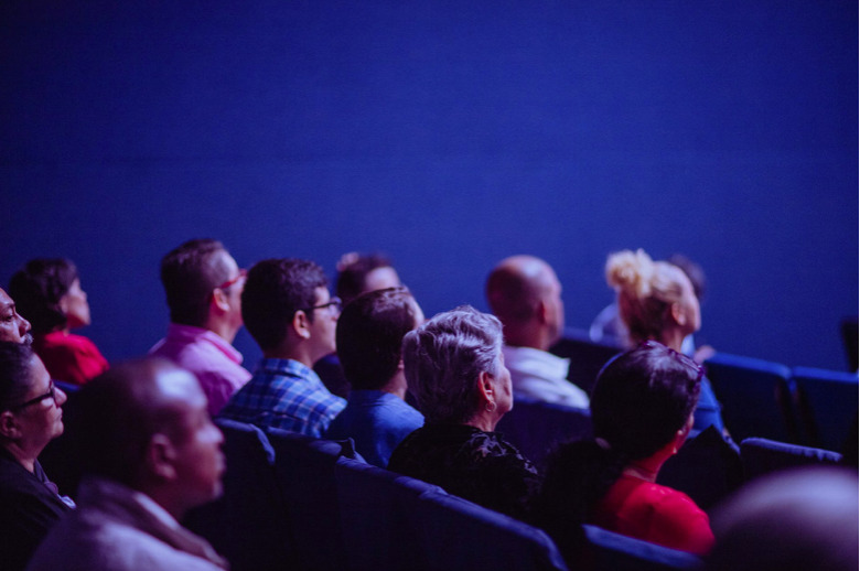 Picture on performative diversity. People sitting in a dark room.