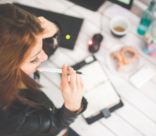 young woman thinking with pen while working studying at her desk