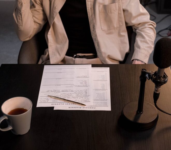 person in white dress shirt sitting beside brown wooden table with white ceramic mug and black