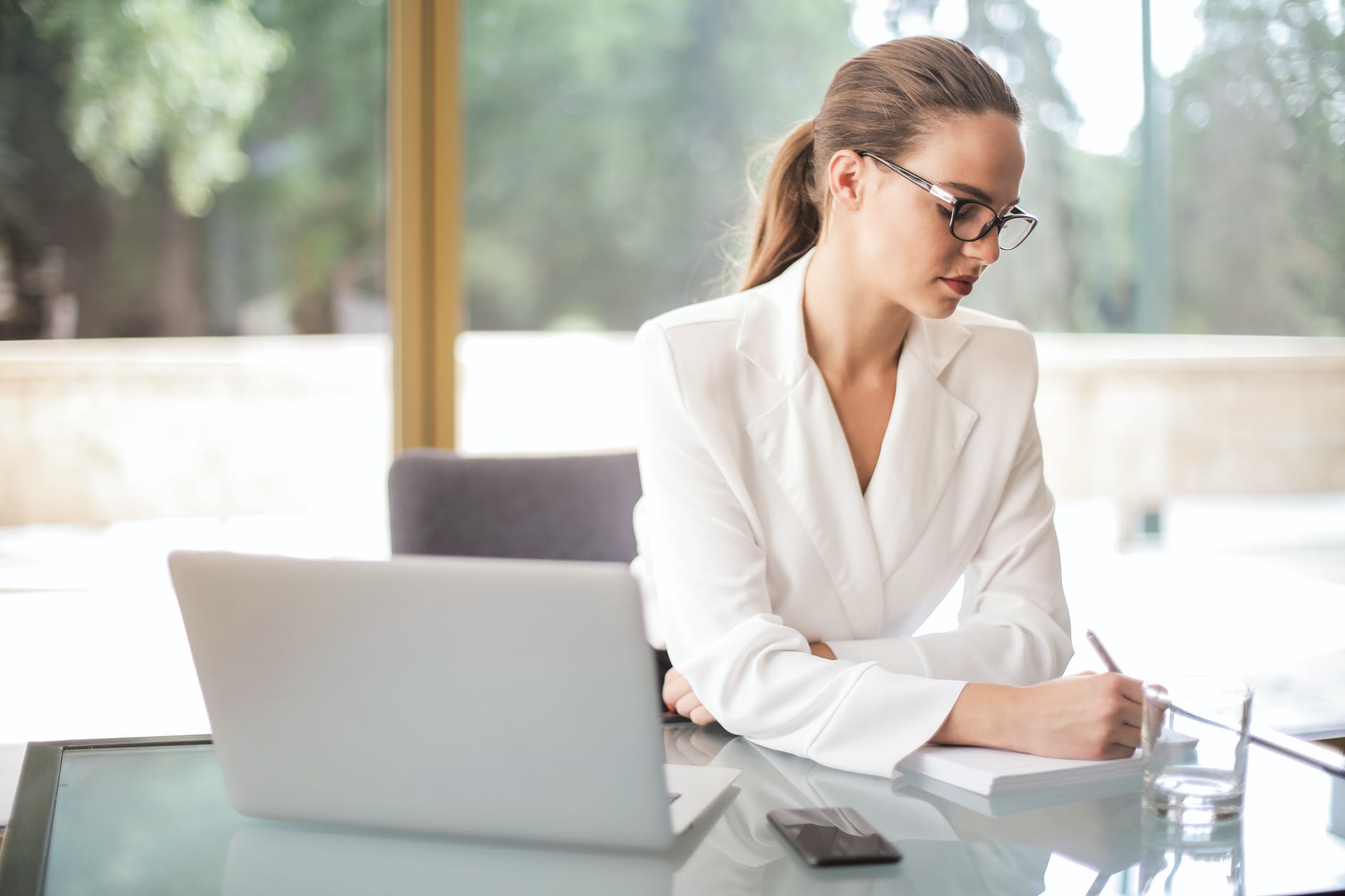 thoughtful businesswoman taking notes in notebook in bright office, 13 Good Reasons to Quit Your Job